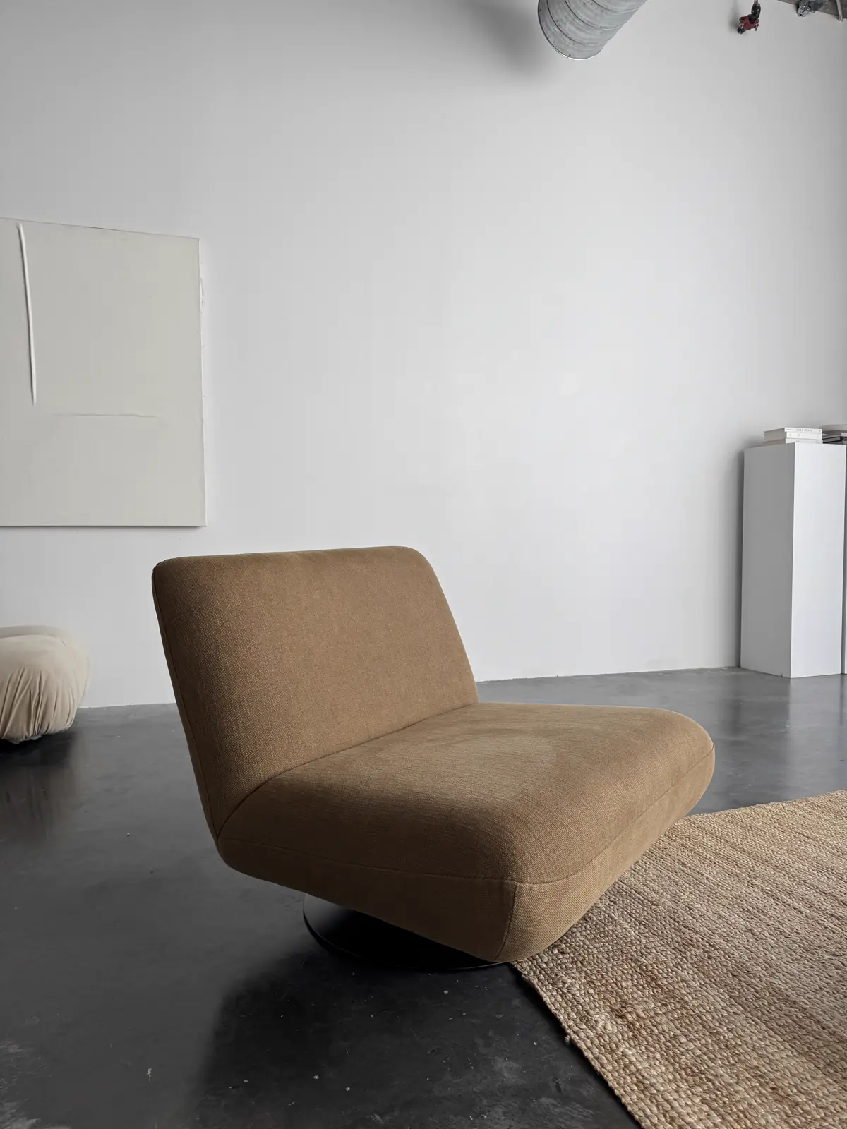 An empty camel leather armchair turned slightly toward a bright window